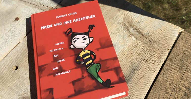 Kinderbuch ‚Marie und ihre Abenteuer‘ auf Holztisch.